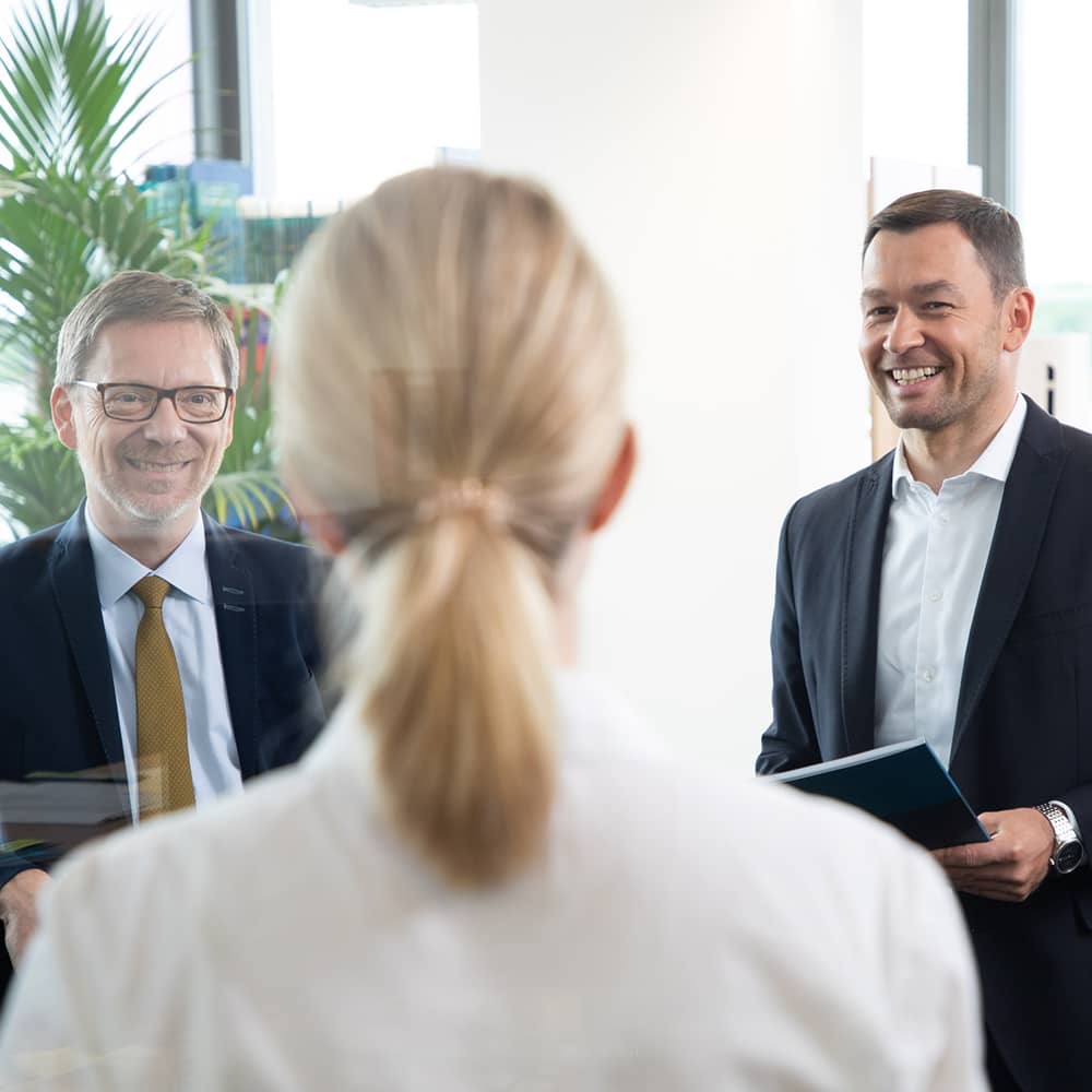  Kollegen, die sich in einem Gespräch auf einer sonnigen Dachterrasse austauschen. 
